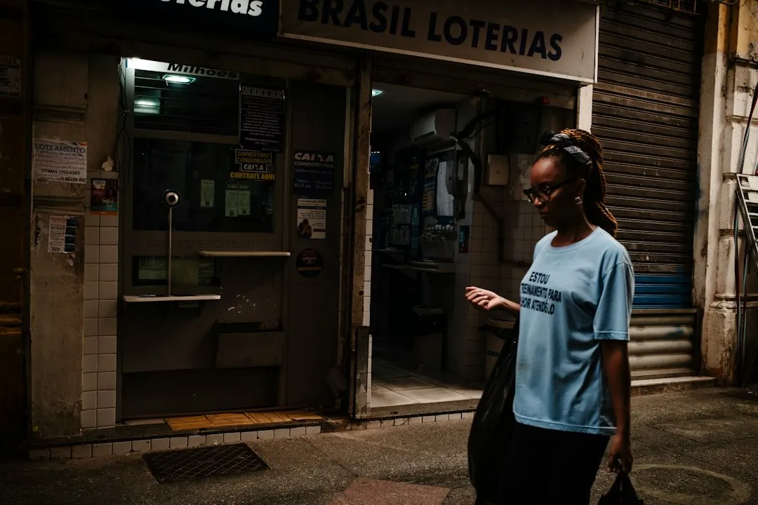 A woman walks past a brasil loterias store at night